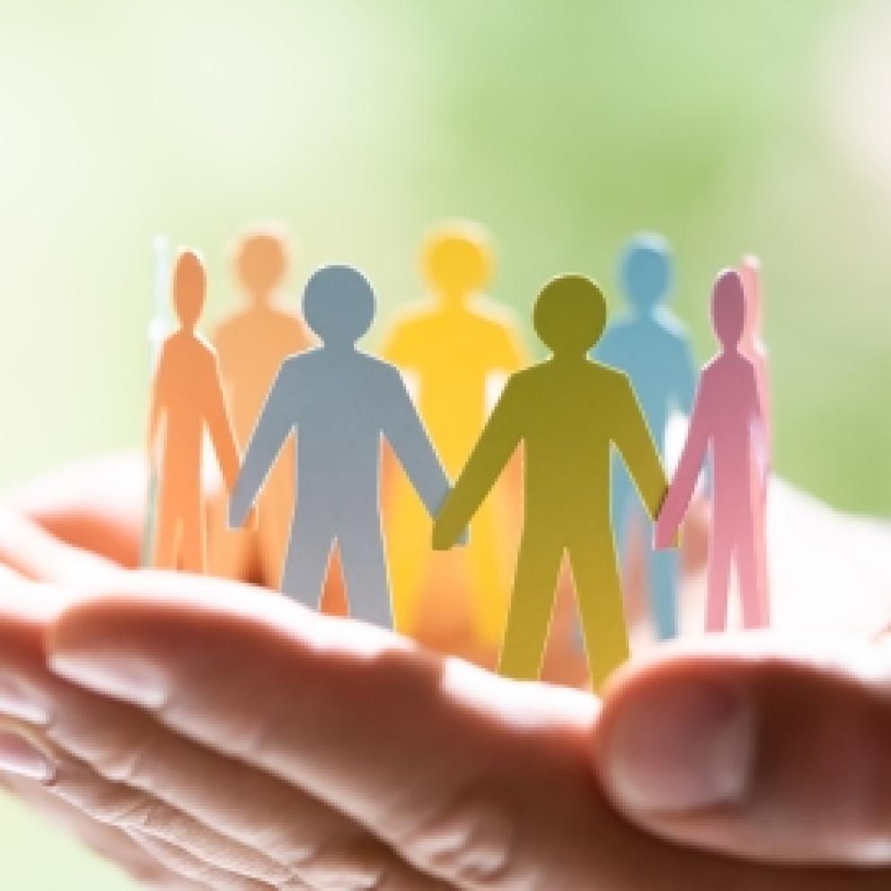 hands holding group of paper people holding hands in circle