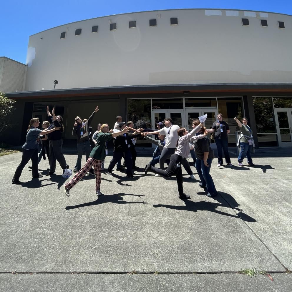 8th graders participating in striking a pose in front of the theatre building