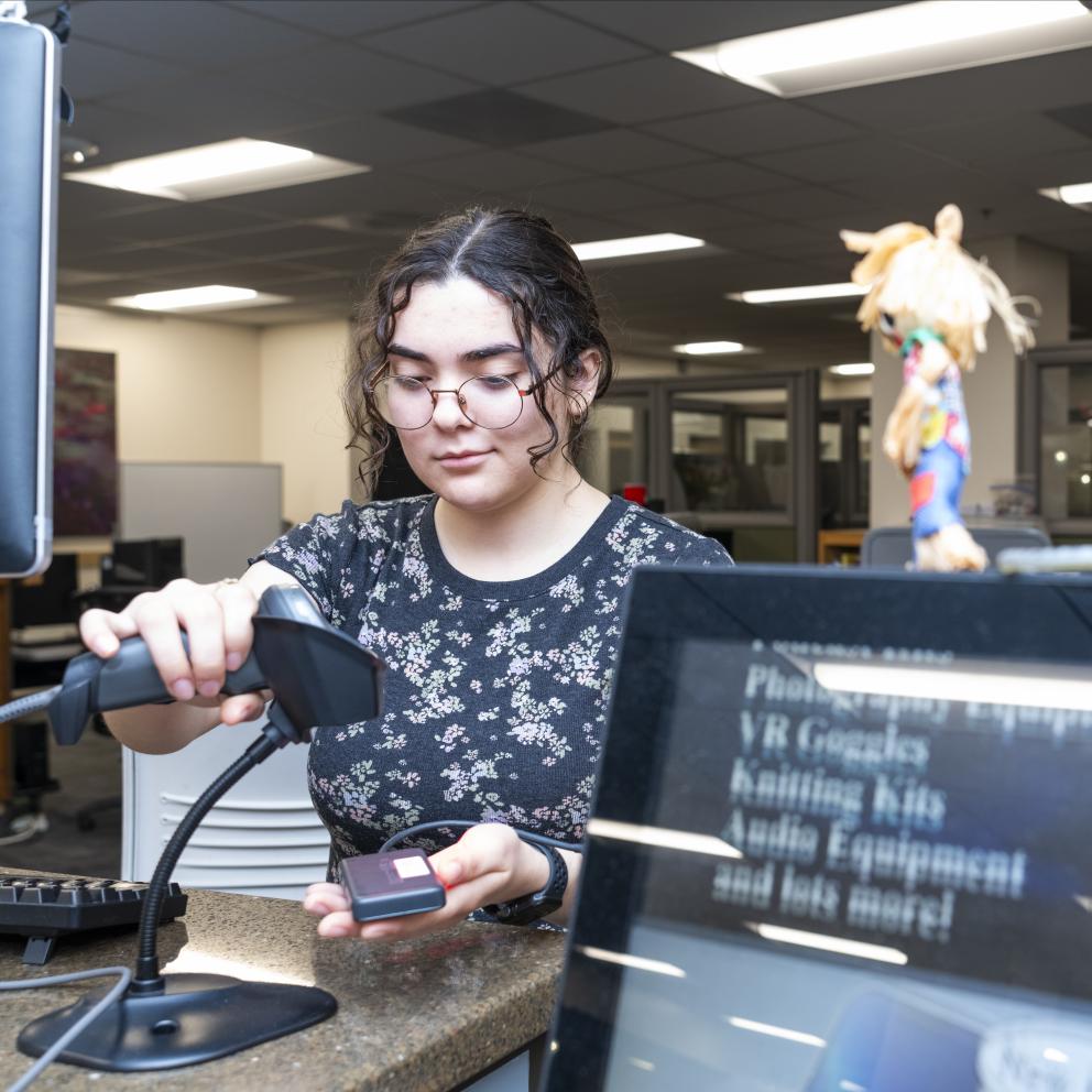 Student employee checks out a charger to a patron
