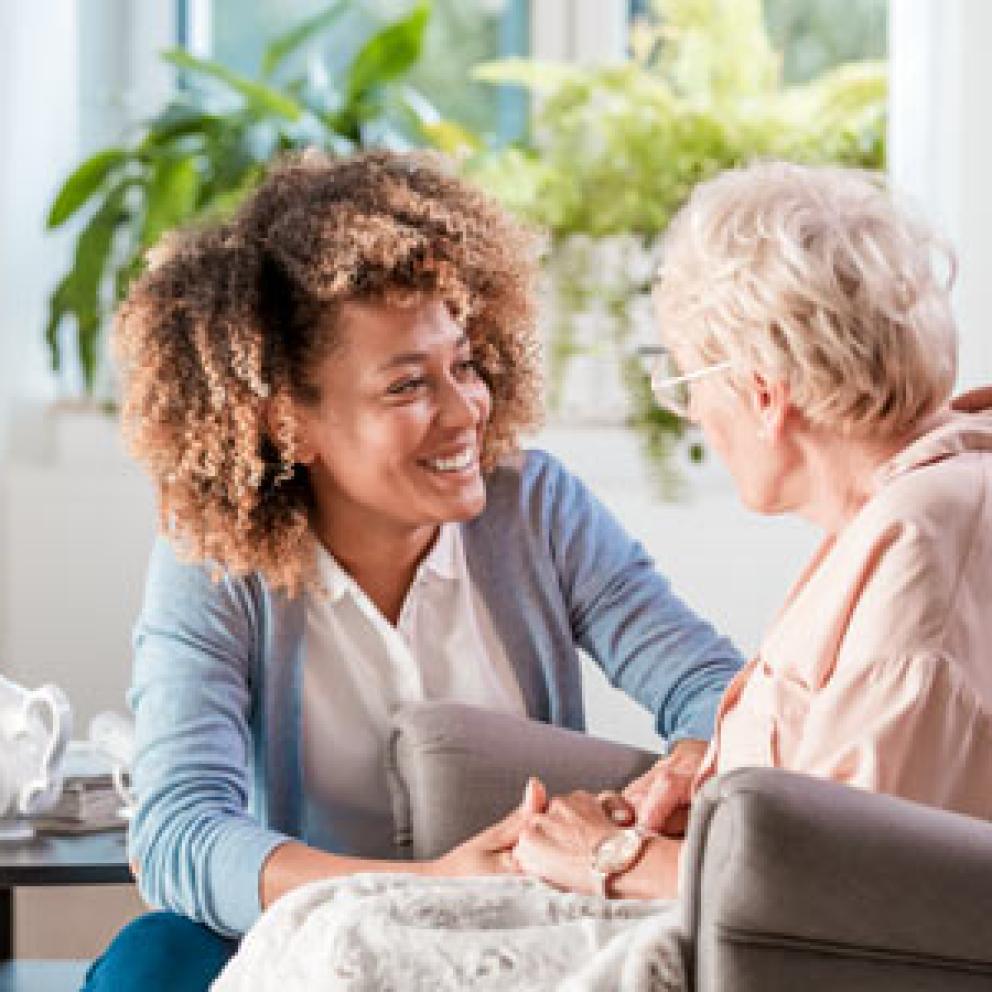 A nurse talking to an older patient sitting in a chair