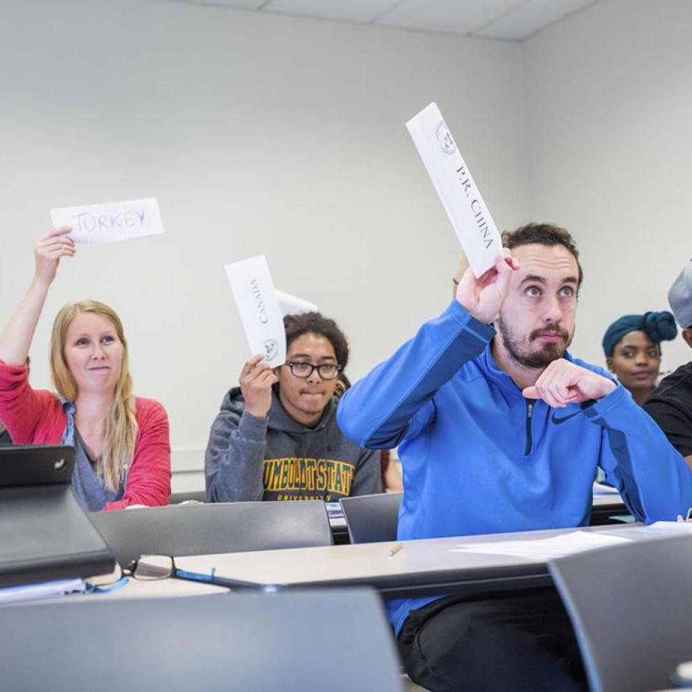 group of students in a classroom holding up name tags with country names