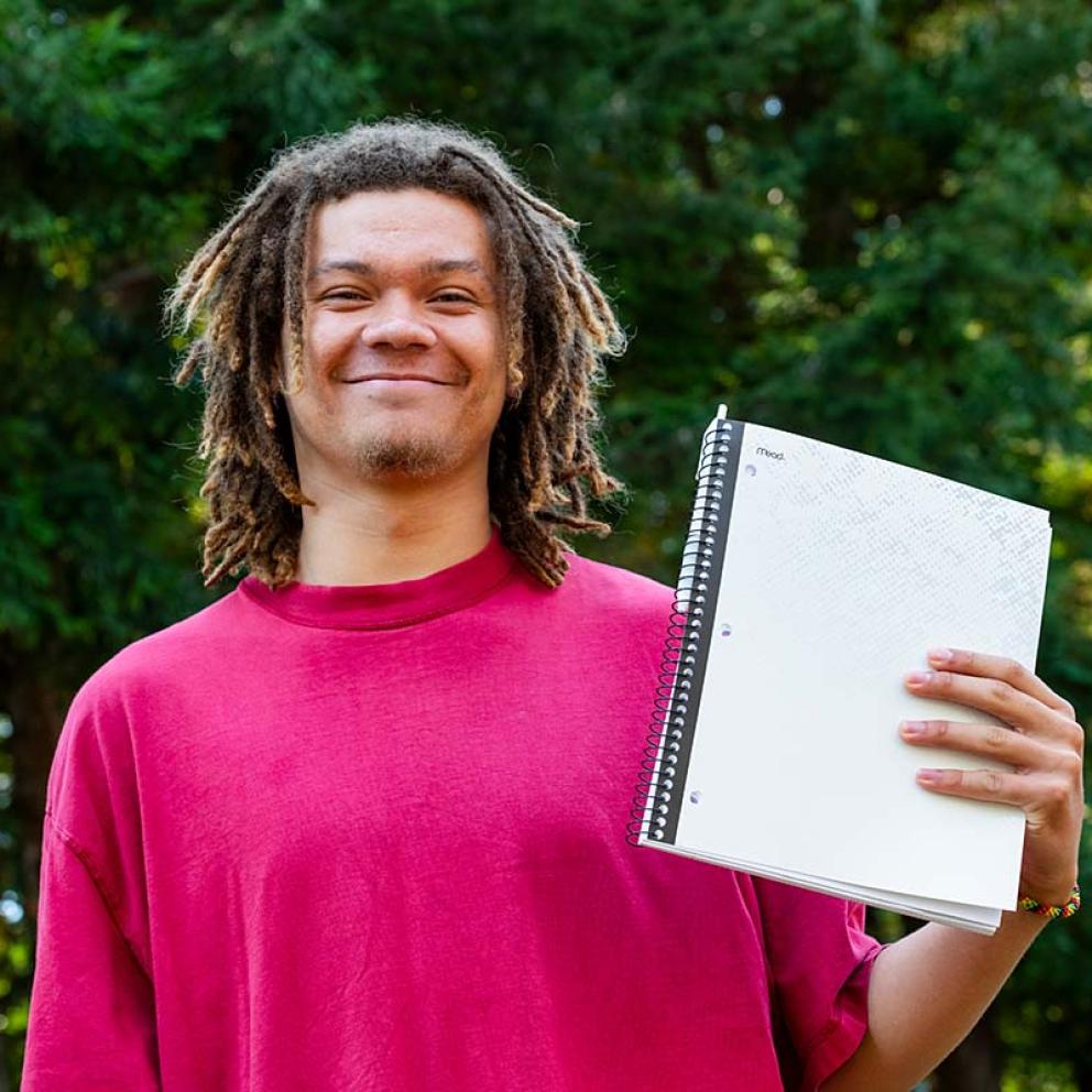 Student holding notebook outside