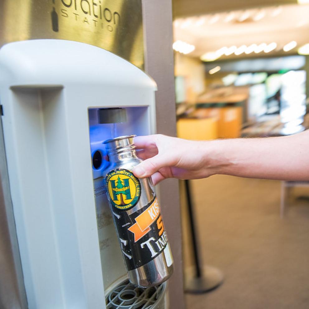 a hand filling a water bottle at one of the hydration stations
