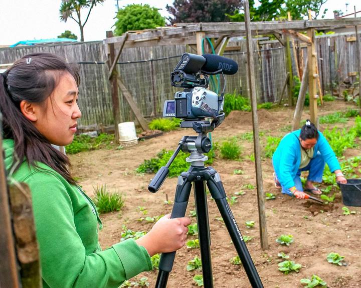 Student filming at community garden project