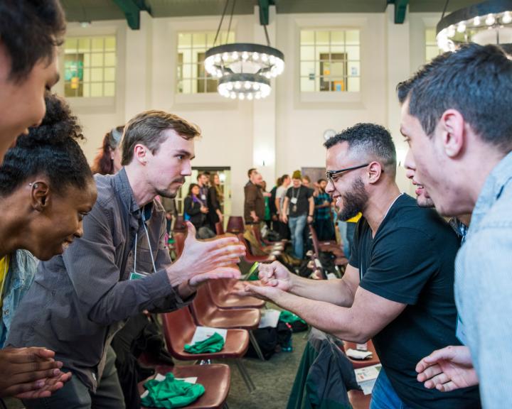 a group of guys at a bar and two of them playing rock paper scissors