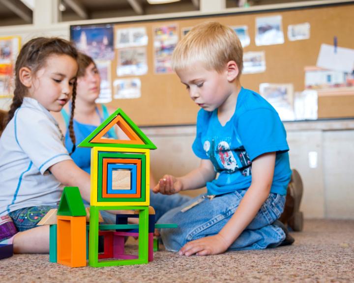 two kids sitting on the ground playing with blocks