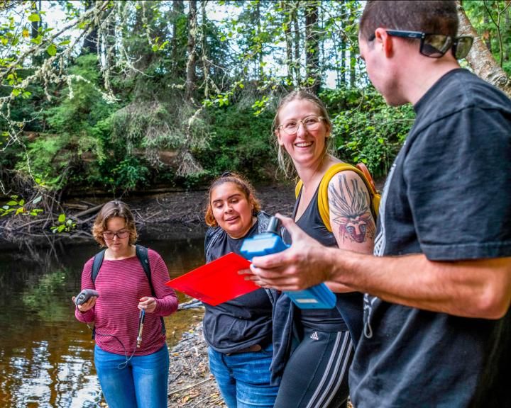 students interacting in front of a body of water