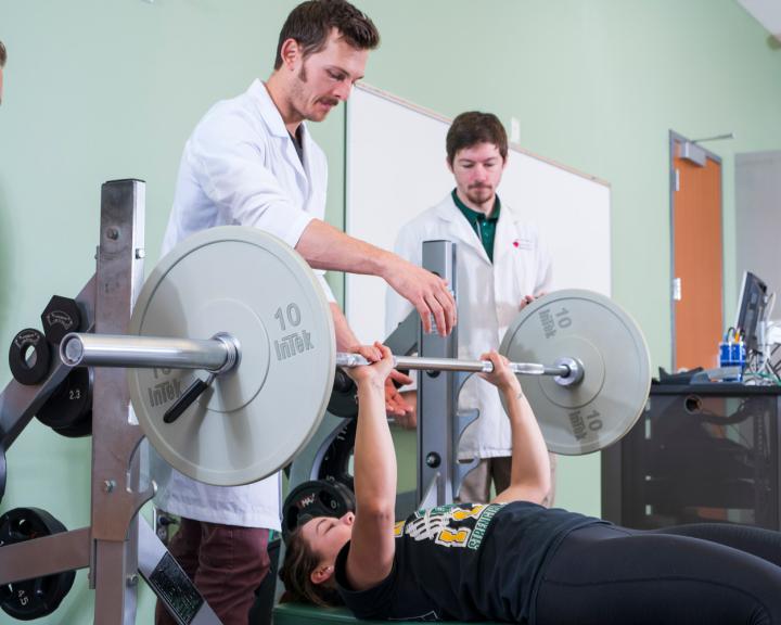 Students using a bench press in a labratory