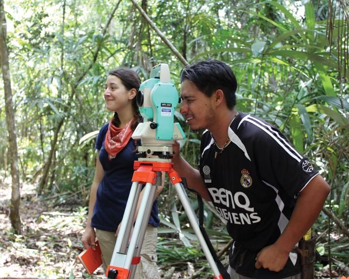 two students looking through a piece of equipment