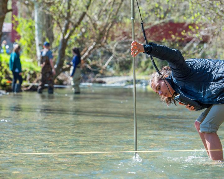 Student measuring the water in a river