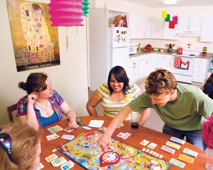 students playing a game at a table in a residence hall room