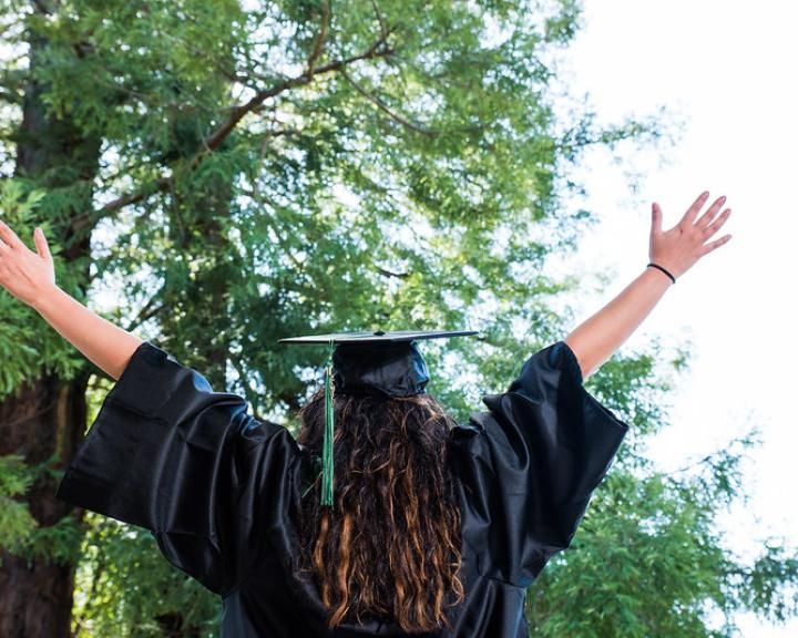 graduating student raises hands in the air