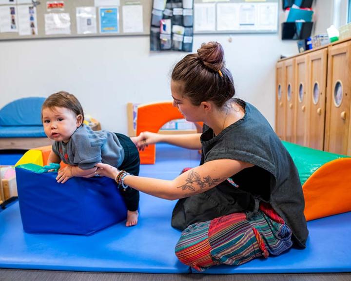 Teacher helping and toddler
