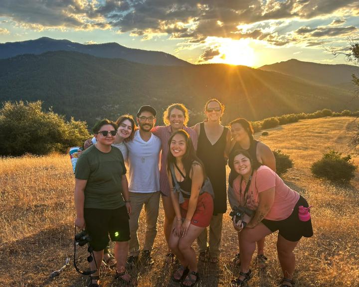 Group of students with sun behind the mountains in background