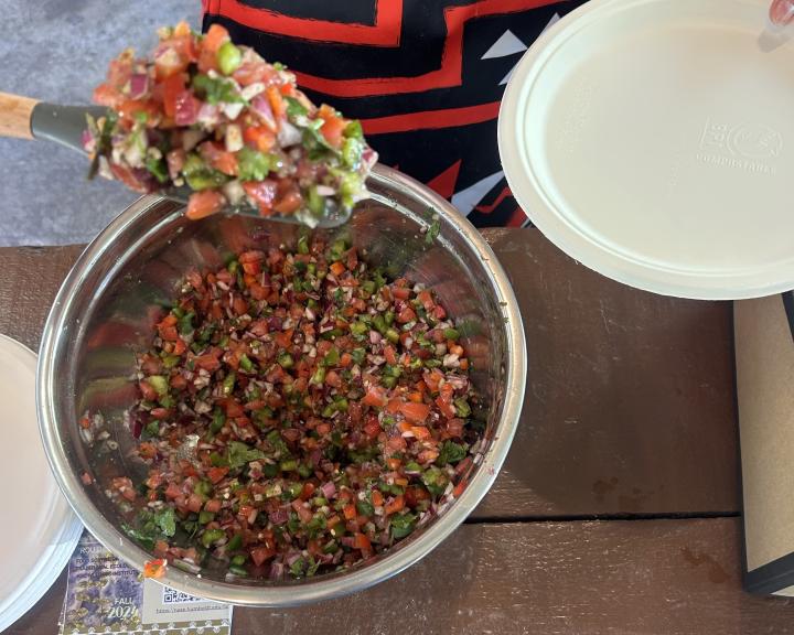Bowl of Paa-moh salsa with FSL member scooping some out onto a plate.