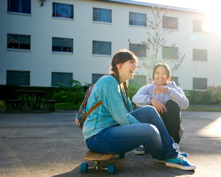 student laughing, sitting on skateboard