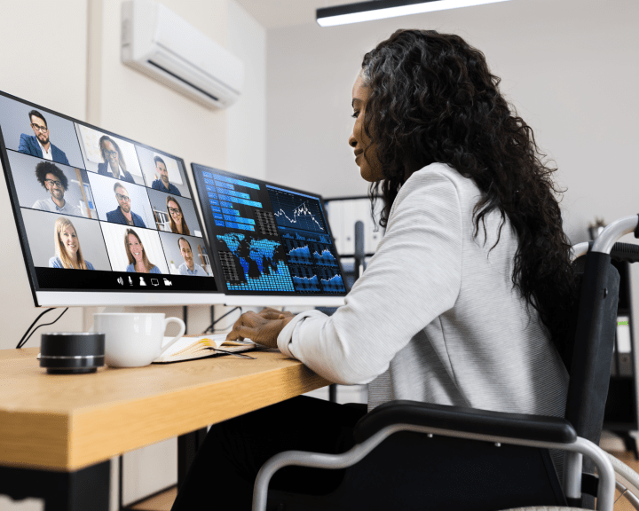 Student in wheelchair on a video meeting with two desktops