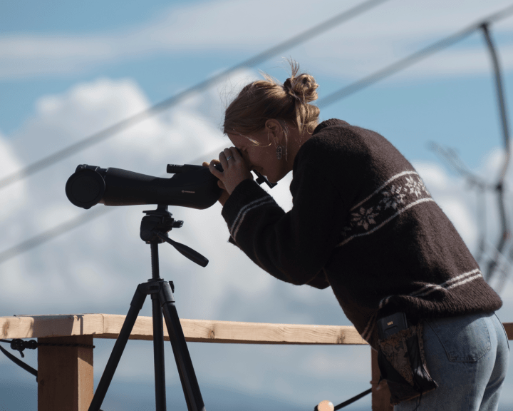 Person looking through telescope camera outside