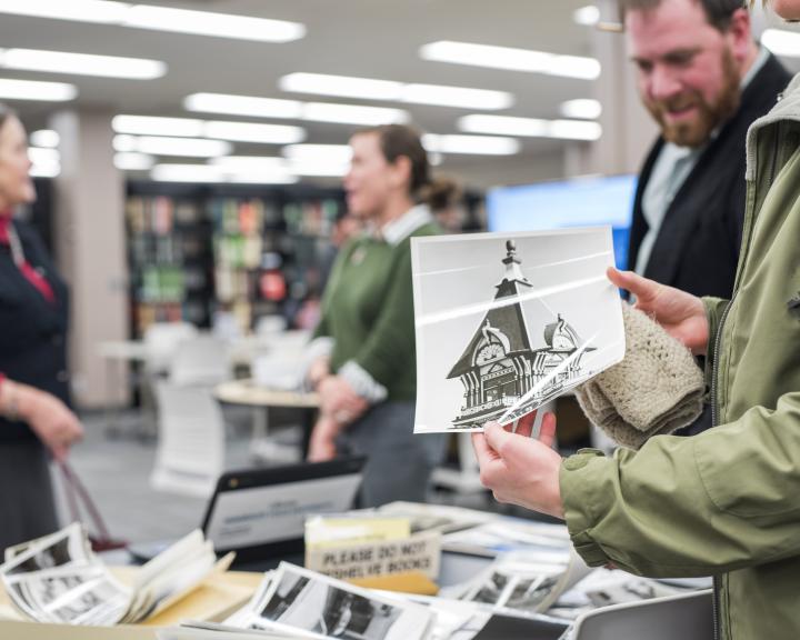 Photo of people in special collections holding photo of top of carson mansion