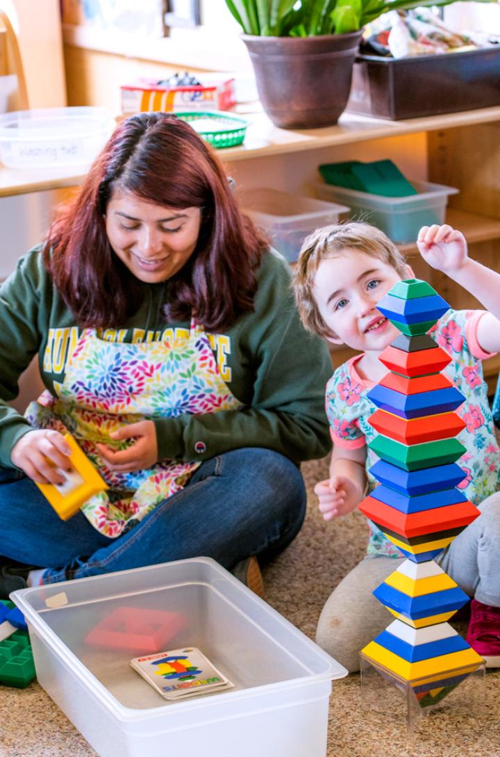 Teacher sitting with two students playing with blocks