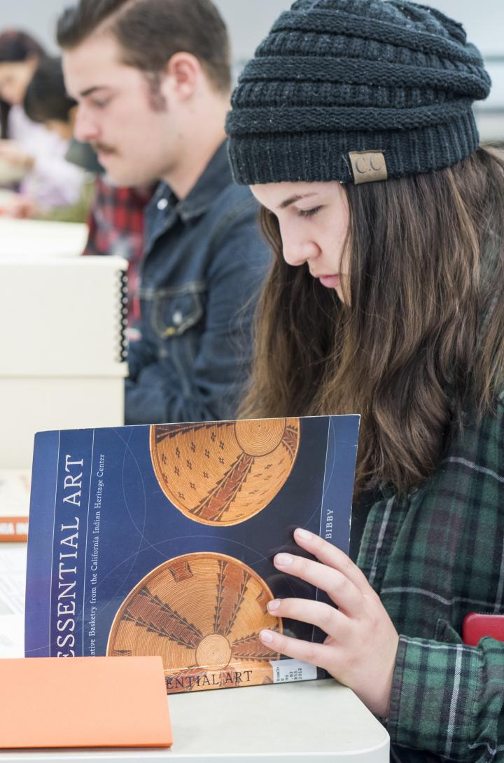 Eight students researching in special collections with books open on a table