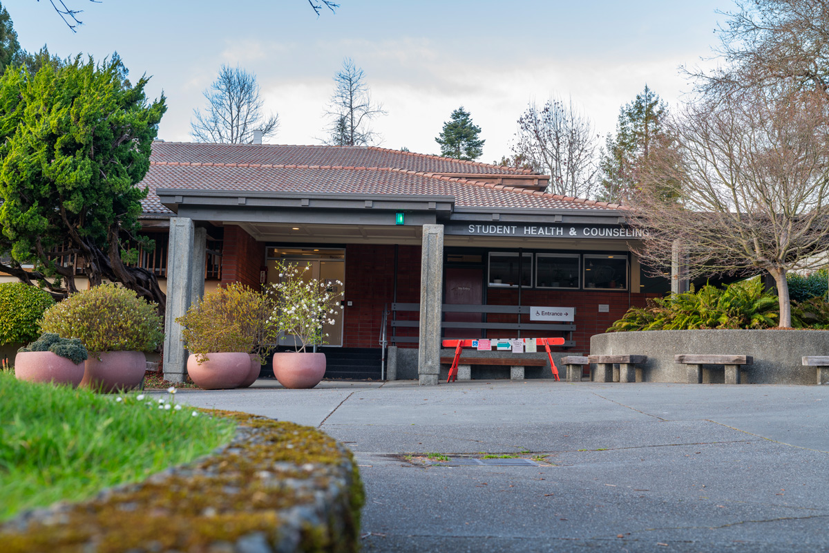 Front of the wellbeing building, gray building with two pillars and many planters out front