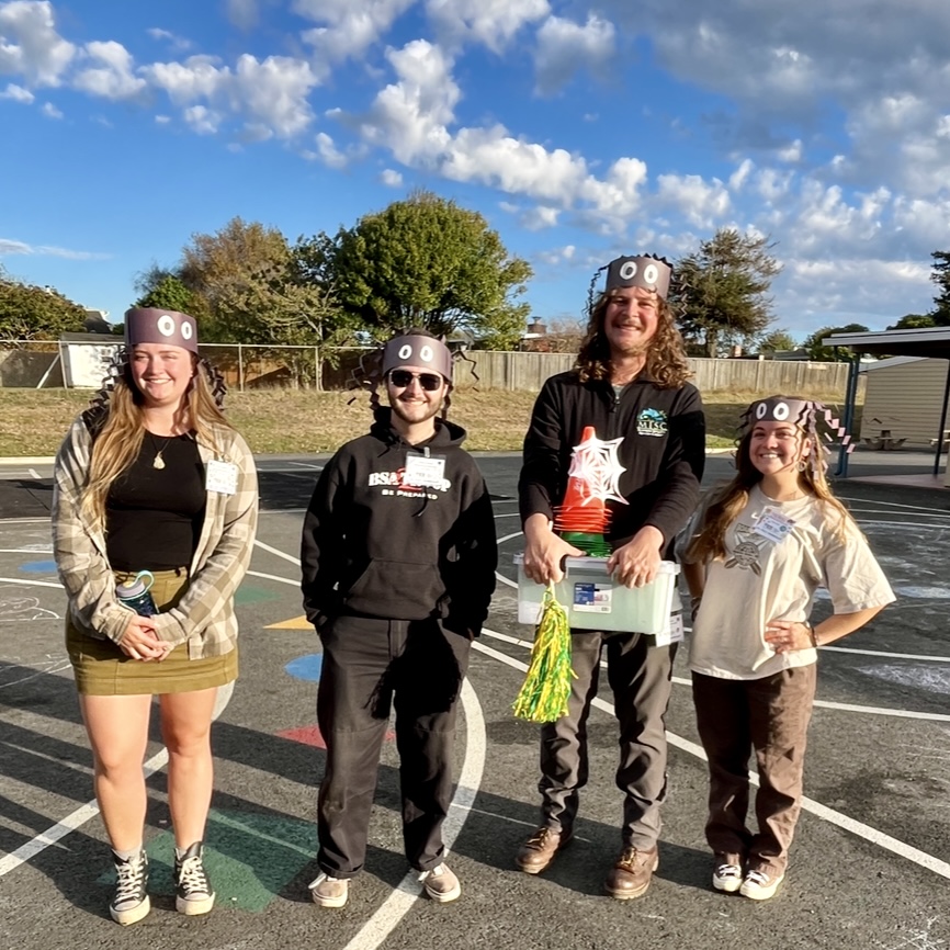 Four EE volunteers wear paper spider crowns at Alice Birney Elementary