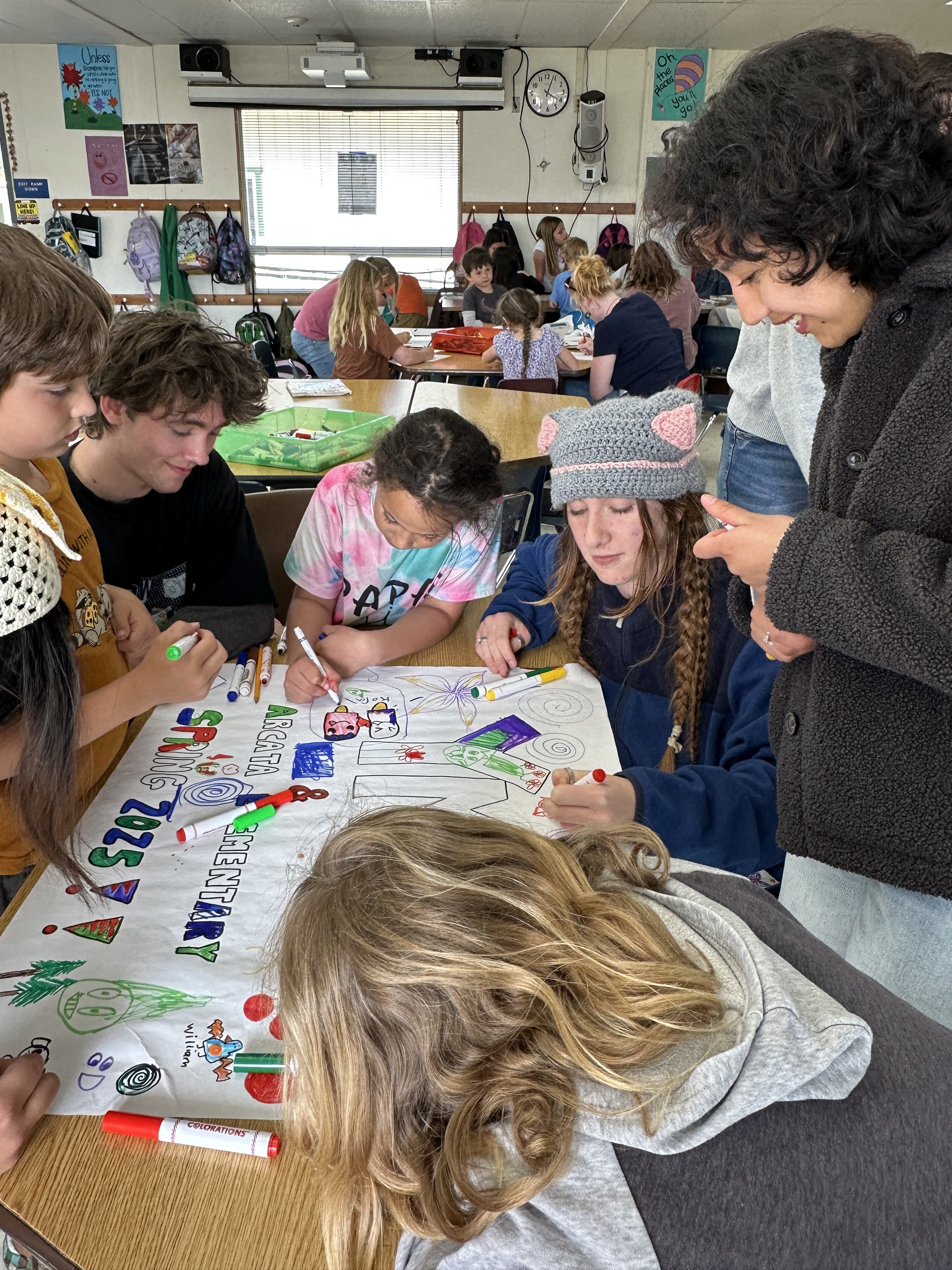YMP volunteers decorate a paper banner with children at Arcata Elementary After School Program (Spring 2025)