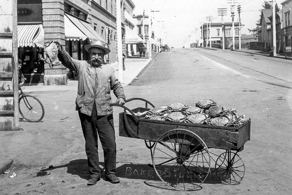 black and white photo of a man with a cart full of crabs